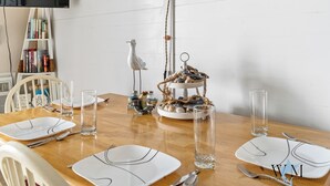 A dining table set with white plates, cutlery, and clear glasses, with a decorative centerpiece and a white chair in the background. - 1 Bedroom Ocean View Condo with Community Pool (Ocean City)