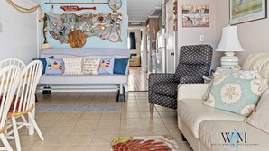 A cozy living room with a sofa, chairs, and a decorative wall. - 1 Bedroom Ocean View Condo with Community Pool (Ocean City)