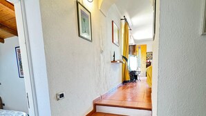 Un escalier avec des marches en terre cuite et des bords blancs, menant à une pièce où se trouvent un lit et une porte.