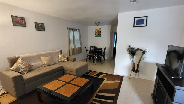 Una sala de estar con sofá, mesa de centro, televisor y comedor.