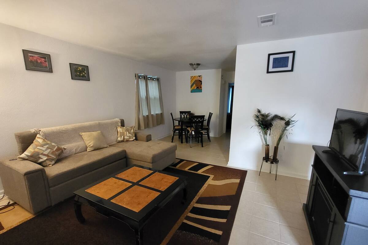 Una sala de estar con sofá, mesa de centro, televisor y comedor.