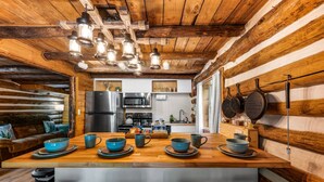 A rustic kitchen with wooden walls, a wooden dining table with blue bowls, and a black refrigerator.