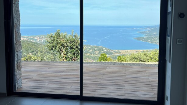 A room with a large sliding glass door leading to a balcony with a view of the sea and hills. - Apartment (Viggianello)