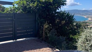 Une voiture est garée devant une maison qui offre une vue sur une plage et des montagnes en arrière-plan.