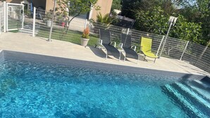 A swimming pool with clear water, surrounded by a fence, and a few lounge chairs. - Villa with pool and air conditioning (Carpentras)
