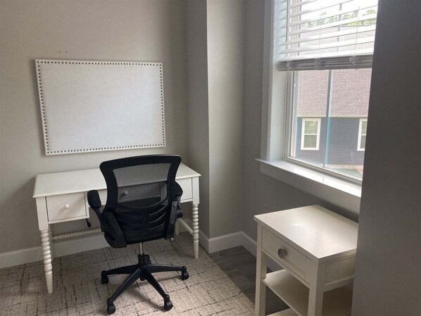 Un petit bureau comprenant un bureau, une chaise et une fenêtre.