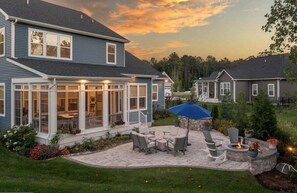 A two-story house with a covered patio, outdoor seating, and a fire pit.