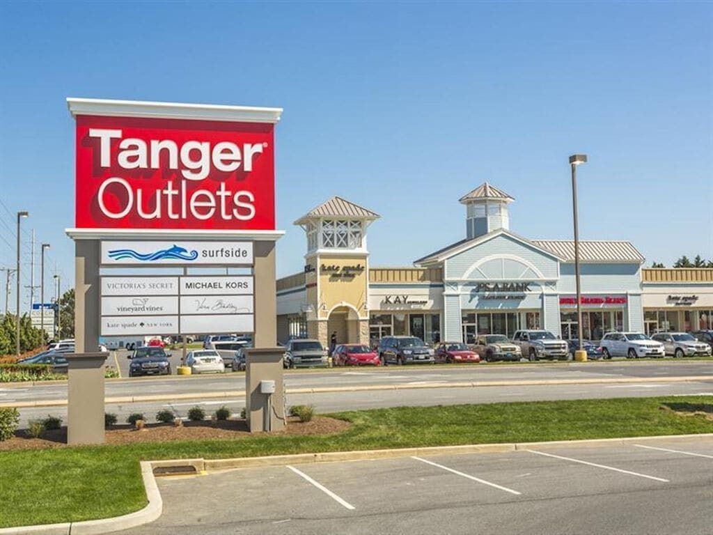 Un panneau indiquant l’emplacement de Tanger Outlets, avec le logo de la marque Surfside, un parking et divers magasins, dont Kay et PCARANK.