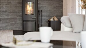 Una sala de estar moderna con una chimenea de leña, un sofá y una mesa de centro.