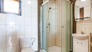 Een badkamer met een toilet, een douche met glazen wanden en een wastafel.