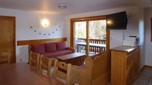 A cozy room with a wooden table, a sofa, and a television mounted on the wall. - Ground floor, terrace, tv, ski locker, 72m², Champagny-en-Vanoise (Champagny-en-Vanoise)