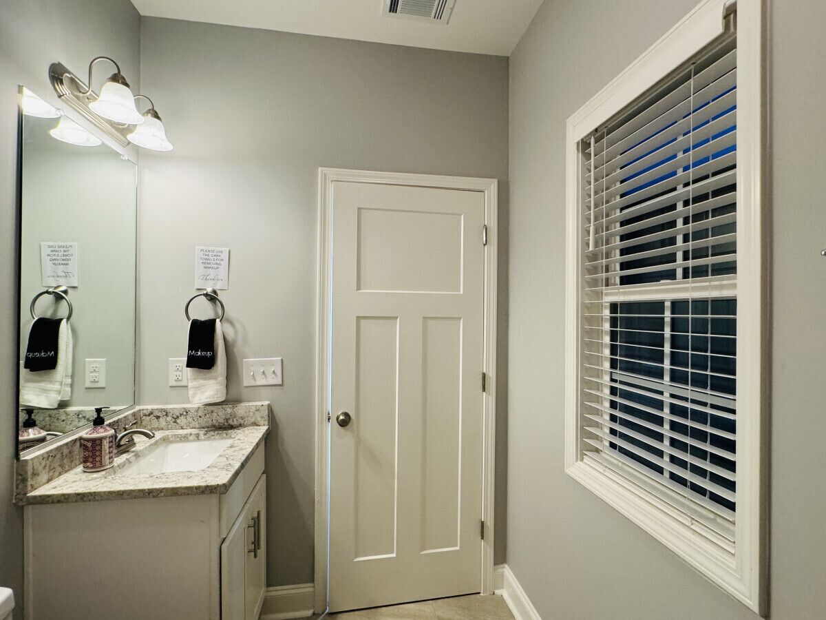 A bathroom with a sink, mirror, towel rack, and a door.