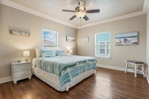 Quarto com cama, duas mesas de cabeceira, ventilador de teto e janela com persianas.