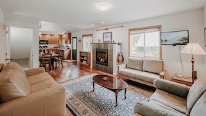 A spacious living room with a fireplace, a sofa, a coffee table, and a television. - 77mbr - Wi-fi - Fireplace - Pets Ok - Bbq 3 Bedroom Cabin by RedAwning (Deming)