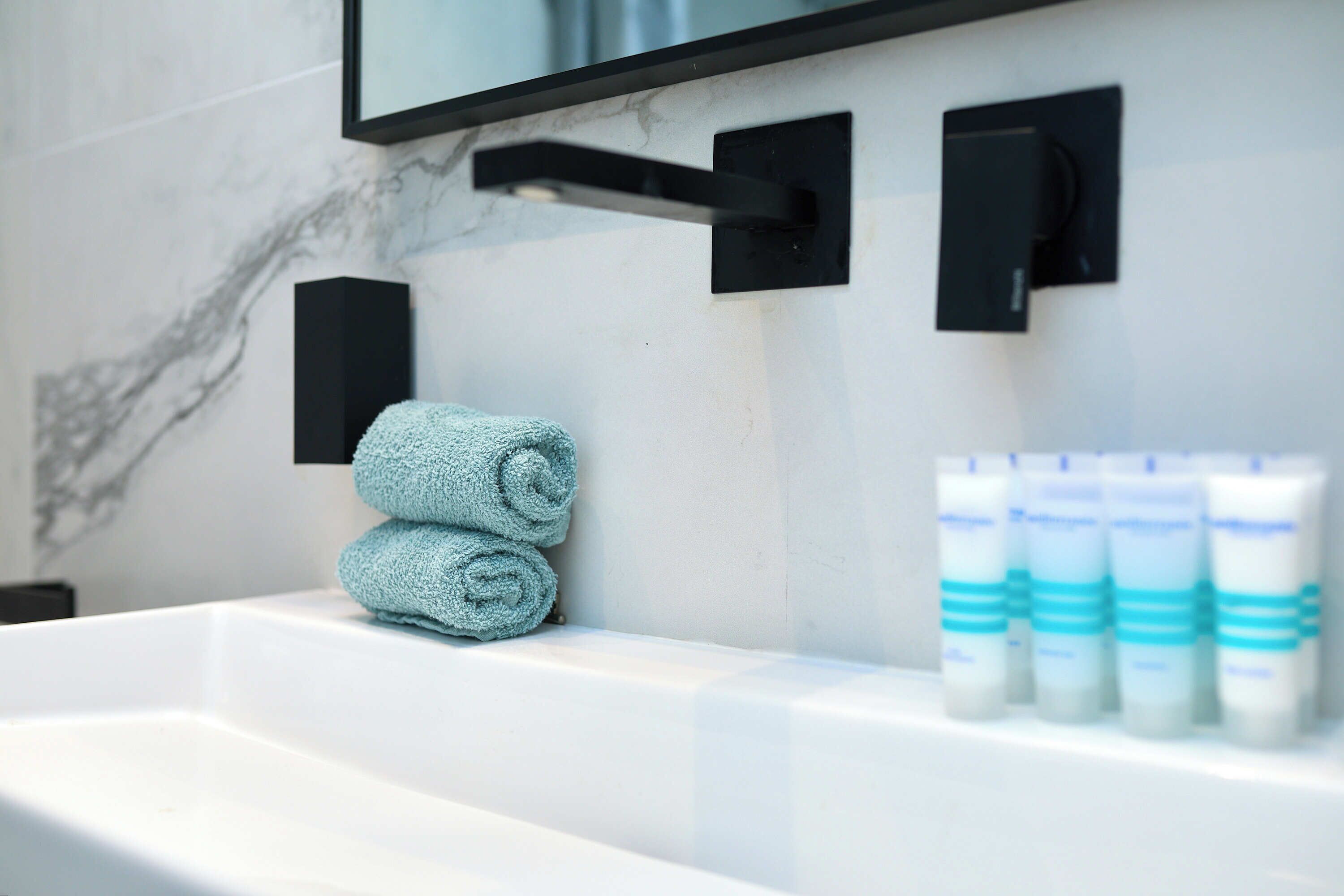 A bathroom with a white sink, a towel, and toiletries.