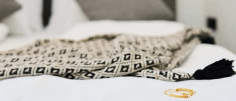 A bed with a patterned blanket and a black tassel, a gold bracelet, and a pillow.