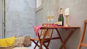 A wooden table with a bottle of champagne, two glasses, and a candle. There are wicker baskets and a red and white checkered cloth on the table. - Black Water Bay house (Dubrovnik)