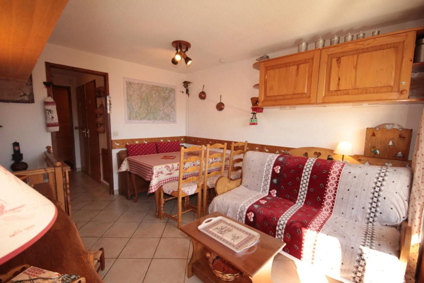 A cozy living room with a sofa, a dining table with chairs, and a kitchen area with wooden cabinets.