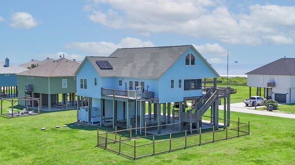 A coastal house with a raised deck, solar panels, and a view of the ocean.
