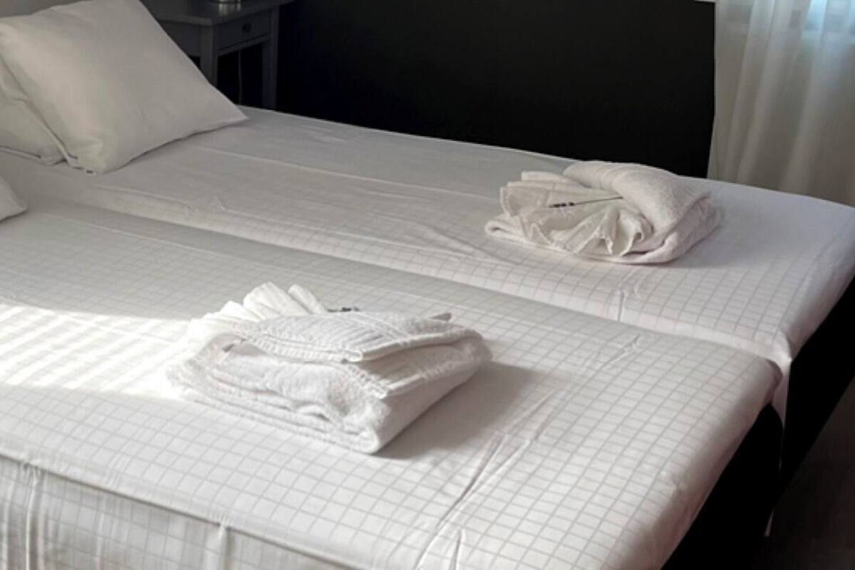 A hotel room with two beds, each with a neatly folded white towel and a pillow.