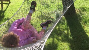 Un niño acostado en una hamaca en un área con césped.