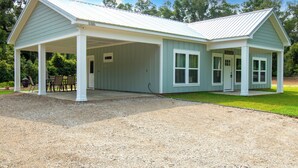 A two-story building with a covered porch and a gravel driveway. - Hundred Mullet Hotel- New Home Near Foley  (Foley)