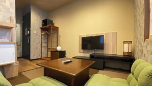 A modern living room with a flat-screen TV, a wooden coffee table, and green upholstered sofas. - My Home Inn Izumisano (Izumisano)