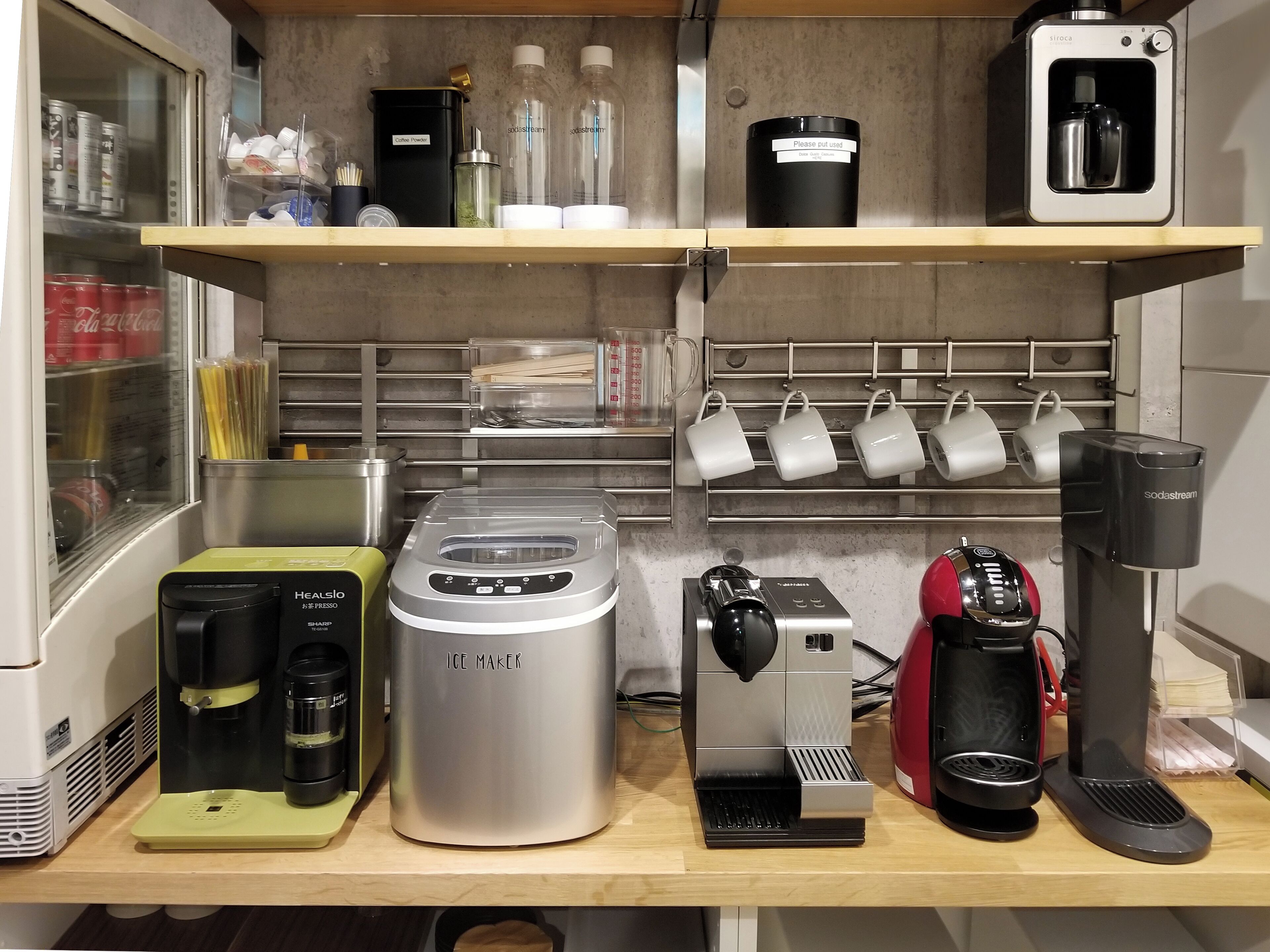 Una kitchenette equipada con cafetera, máquina de hielo, balanza y máquina de café.