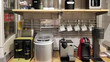 Una kitchenette equipada con cafetera, máquina de hielo, balanza y máquina de café.