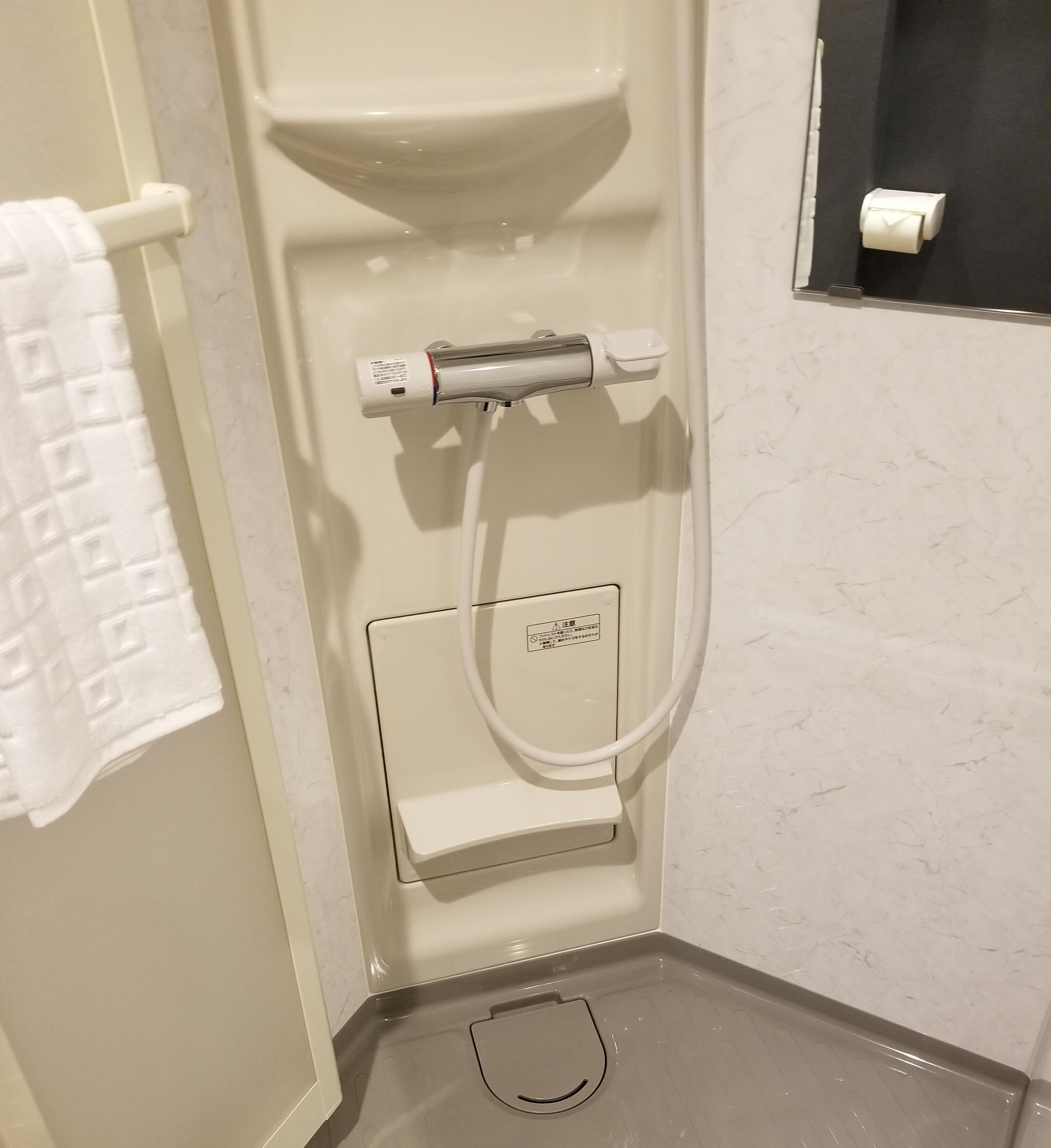 A bathroom with a toilet, a bidet, a towel rack, and a toilet paper holder.