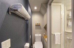 A compact bathroom with a toilet, a towel rack, and a shower area. - My Home Inn Izumisano (Izumisano)