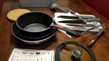 Una cocina equipada con una sartén, espátula y un bloque para cuchillos.