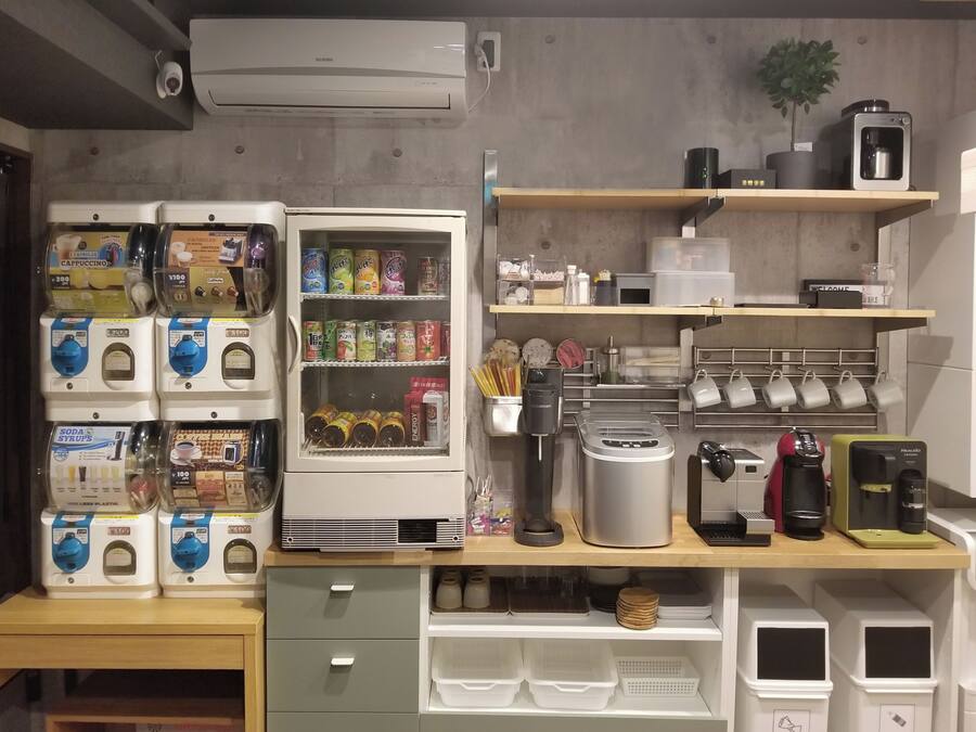 Pieni keittiönurkkaus, jossa on kahvinkeitin, leivänpaahdin ja jääkaappi, joka on täytetty juomilla.