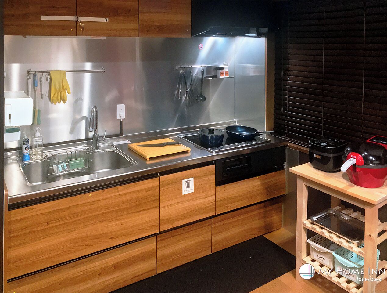 Una cocina moderna con electrodomésticos de acero inoxidable, armarios de madera y una pequeña mesa de madera con utensilios de cocina.