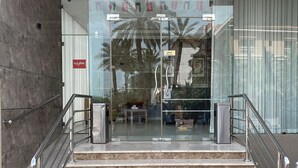 Ein moderner Gebäudeeingang mit Glastüren, Metallgeländern und einer Marmortreppe.