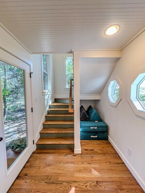 Stairs lead to a cozy seating area with seating and windows.