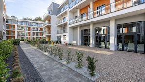 Ett modernt lägenhetskomplex med flera balkonger, en central innergård med sittplatser och en grusbelagd gångväg.