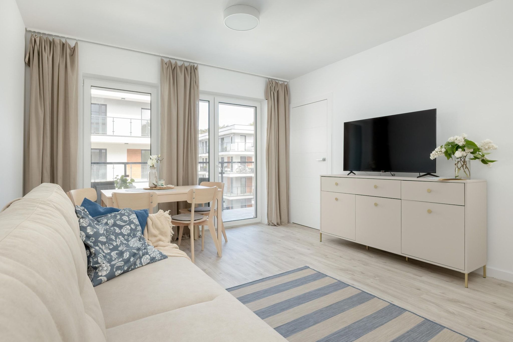 Ein modernes Wohnzimmer mit einer Couch, einem Esstisch und einem Fernseher auf einer Kommode.