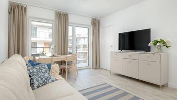 Ein modernes Wohnzimmer mit einer Couch, einem Esstisch und einem Fernseher auf einer Kommode.