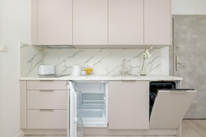 A modern kitchen with a marble backsplash, a built-in dishwasher, and a countertop with a toaster and a vase with flowers.