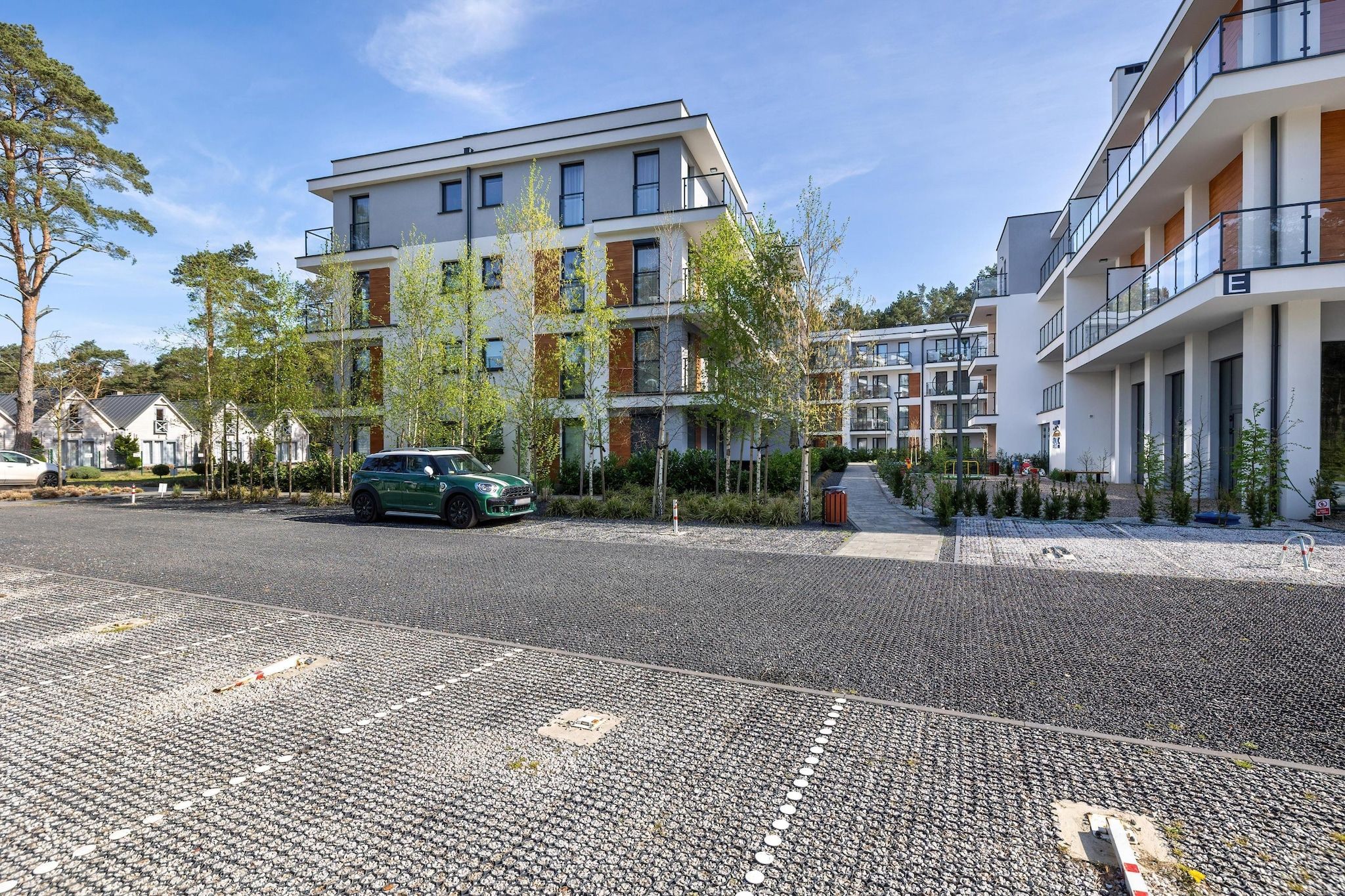Ein modernes, mehrstöckiges Wohngebäude mit Parkplatz voran.
