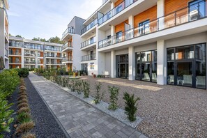 A modern multi-story residential building with balconies, a paved walkway, and a landscaped garden area. - Apartment with balcony, close to the beach, pool (Pobierowo)