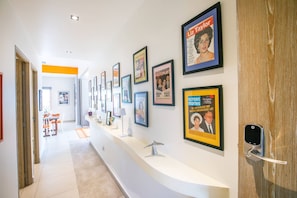 A hallway with framed photographs on the walls, a reception desk, and a door with a Yale lock.