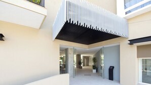 A modern building entrance with a glass door, a staircase, and a black trash bin. - Casa Elizabeth Taylor | Rooftop Pool & Gym (Puerto Vallarta)