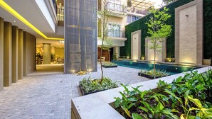A modern indoor courtyard with a swimming pool, potted plants, and a vertical garden. - Casa Elizabeth Taylor | Rooftop Pool & Gym (Puerto Vallarta)