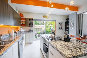 Una cocina moderna con encimeras de granito, electrodomésticos de acero inoxidable y una isla central con asientos.