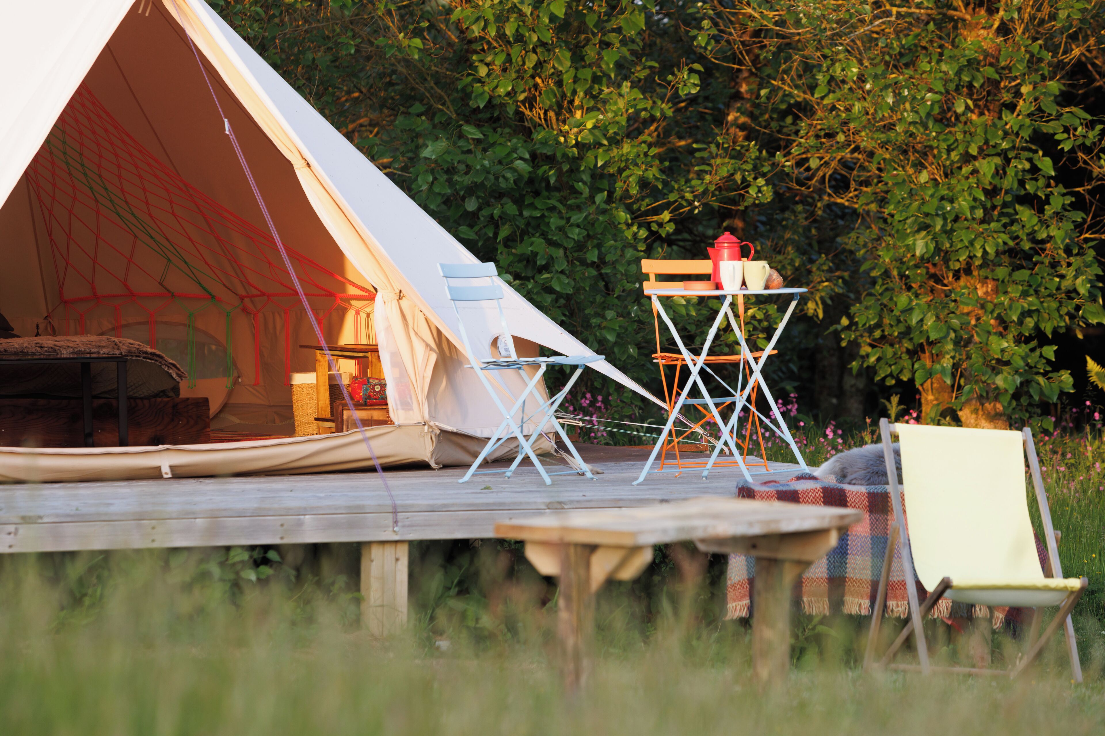 A tent set up in a grassy area with a table and chairs nearby.