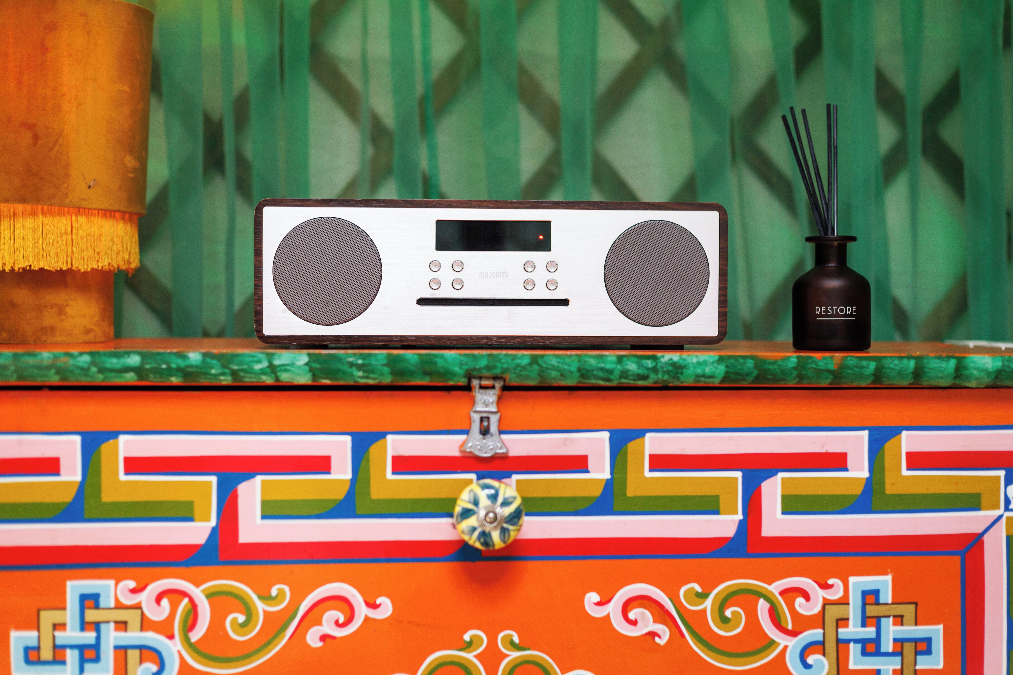A radio and reed diffuser on a colorful, patterned surface.