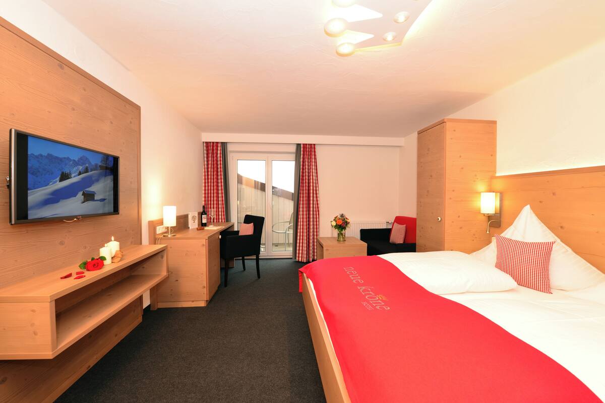 A hotel room with a bed, a desk, a chair, a television, and a view of the outdoors.
