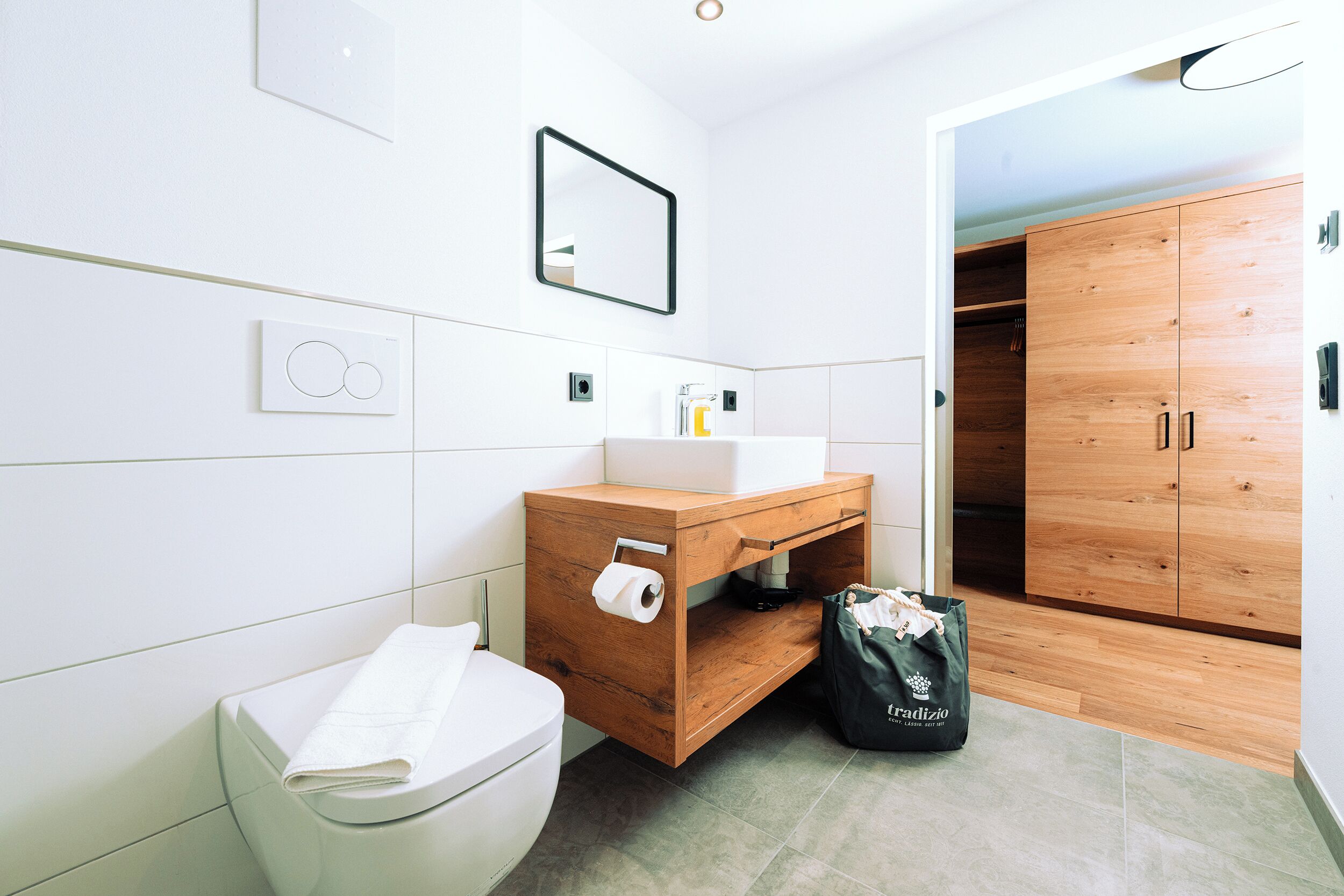 Un baño moderno con tocador de madera, inodoro y armario de madera.